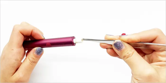 ピンセットを使って詰まったタバコスティックを取り出している画像